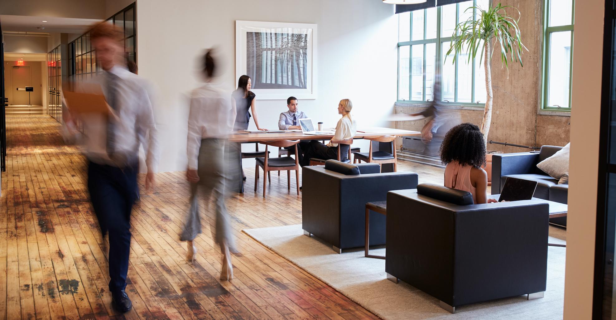 office space with wood floors and people walking