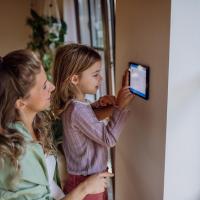 woman and her daughter changing a smart thermostat