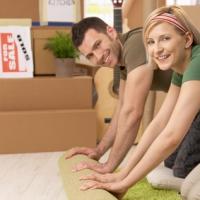 happy couple unrolling carpet in new home