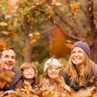 family playing in autumn leaves