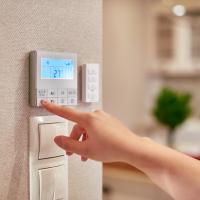 womans hand adjusting thermostat