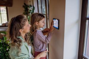 woman and her daughter changing a smart thermostat