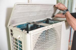 person working on an outdoor air conditioning unit