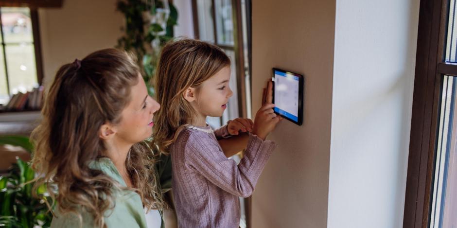 woman and her daughter changing a smart thermostat