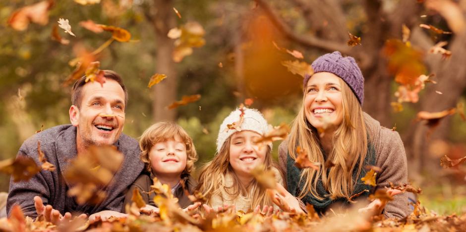 family playing in autumn leaves