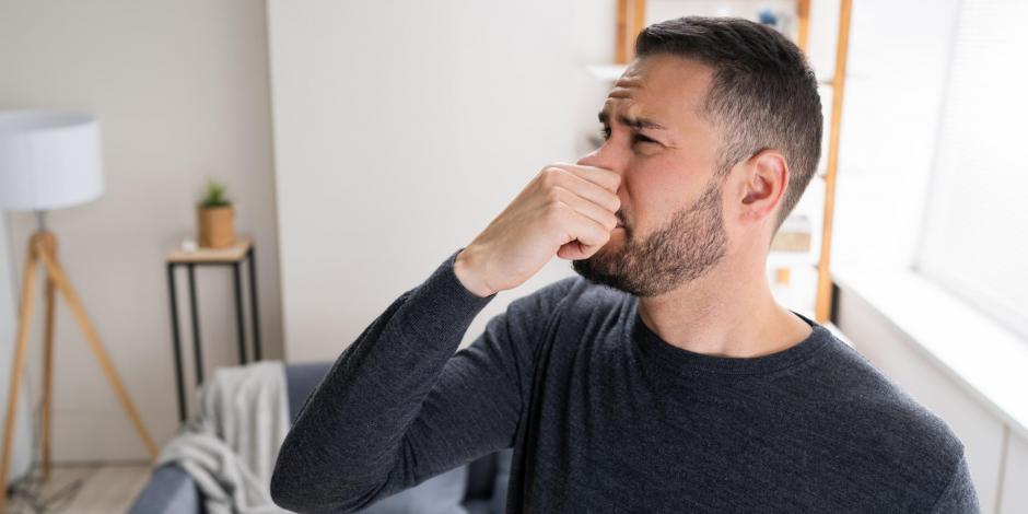 a man holding his nose because the air conditioner smells bad