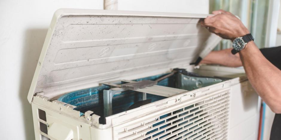 person working on an outdoor air conditioning unit
