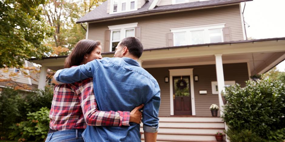 happy couple standing in front of home