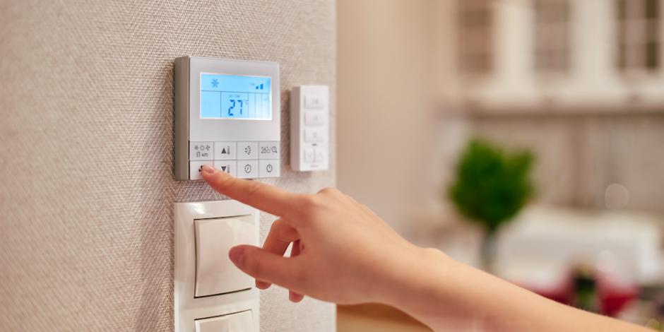 womans hand adjusting thermostat