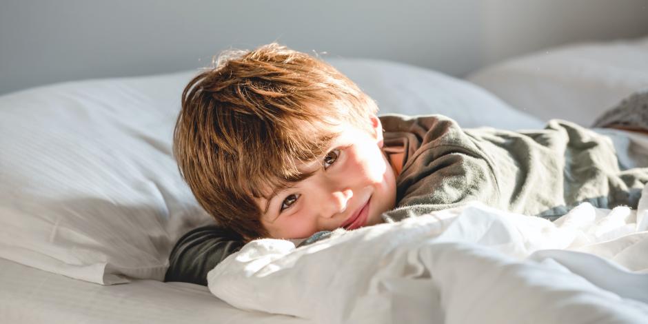 young boy in bed waking up happy